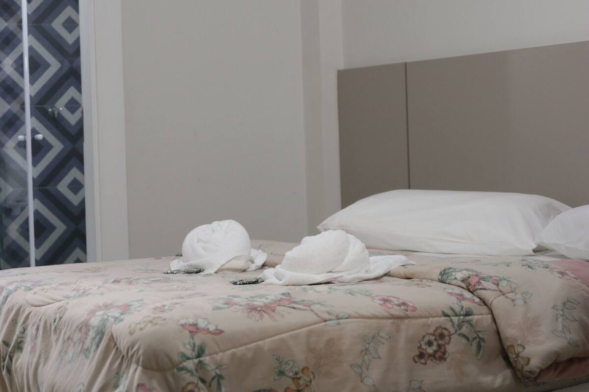 Une chambre d’hôtel avec un lit, un rideau à motifs et un appareil de climatisation.