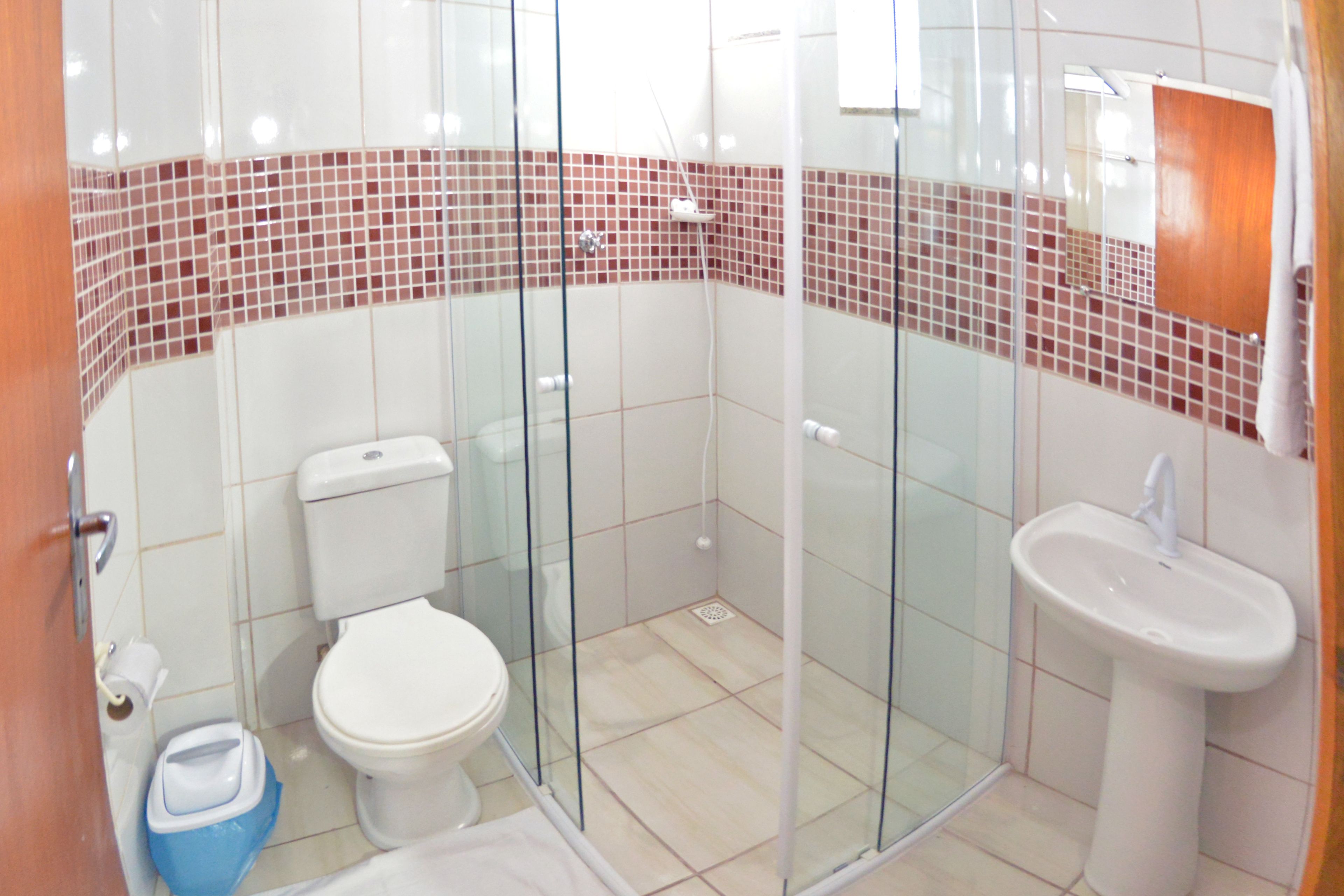 A bathroom with a glass shower enclosure, a toilet, and a sink.