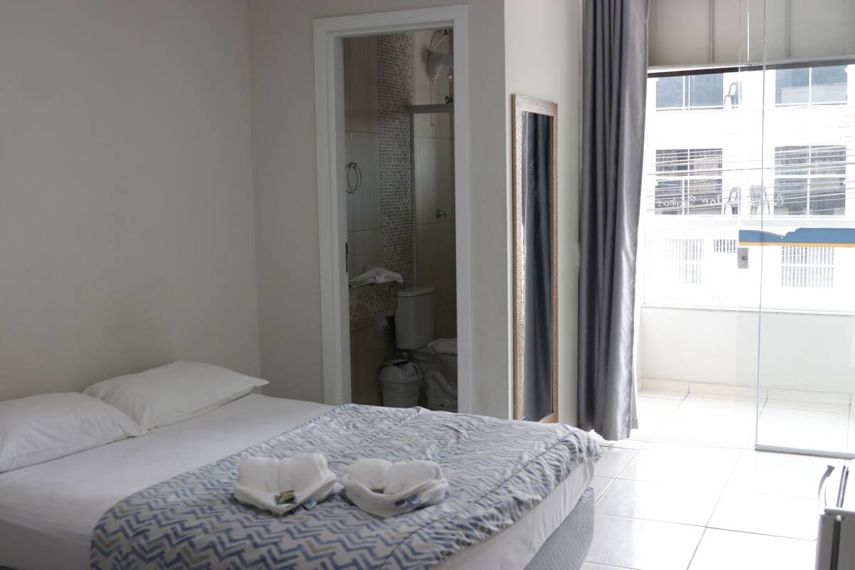 Une chambre d’hôtel avec un lit, une salle de bain avec douche et une vue sur l’extérieur.