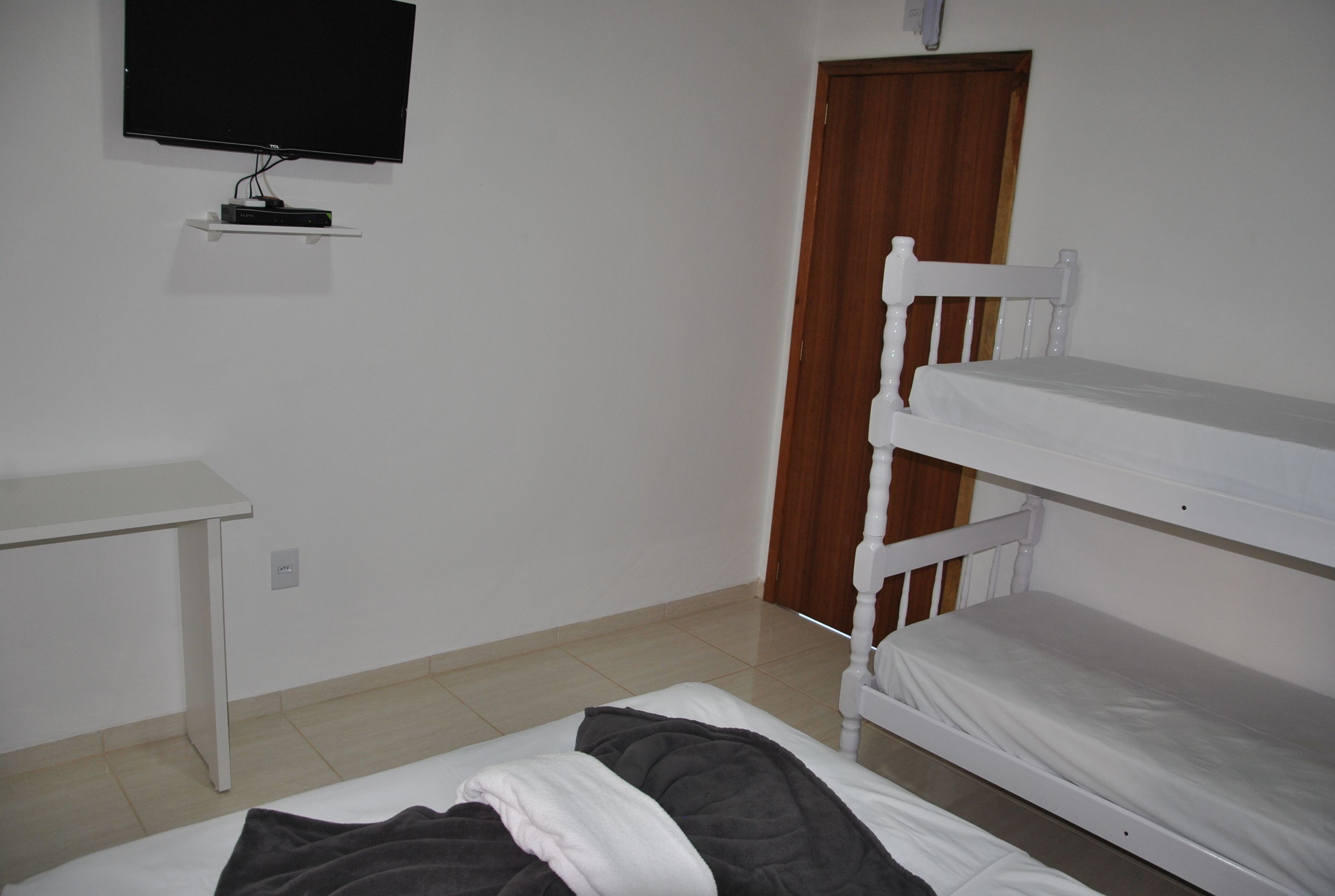 Ein Zimmer mit einem Etagenbett, einem Schreibtisch und einem an der Wand befestigten Fernseher.