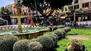 A public square with a central fountain, surrounded by neatly trimmed hedges and a decorative iron fence. - Torremolinos Hostel (Torremolinos)