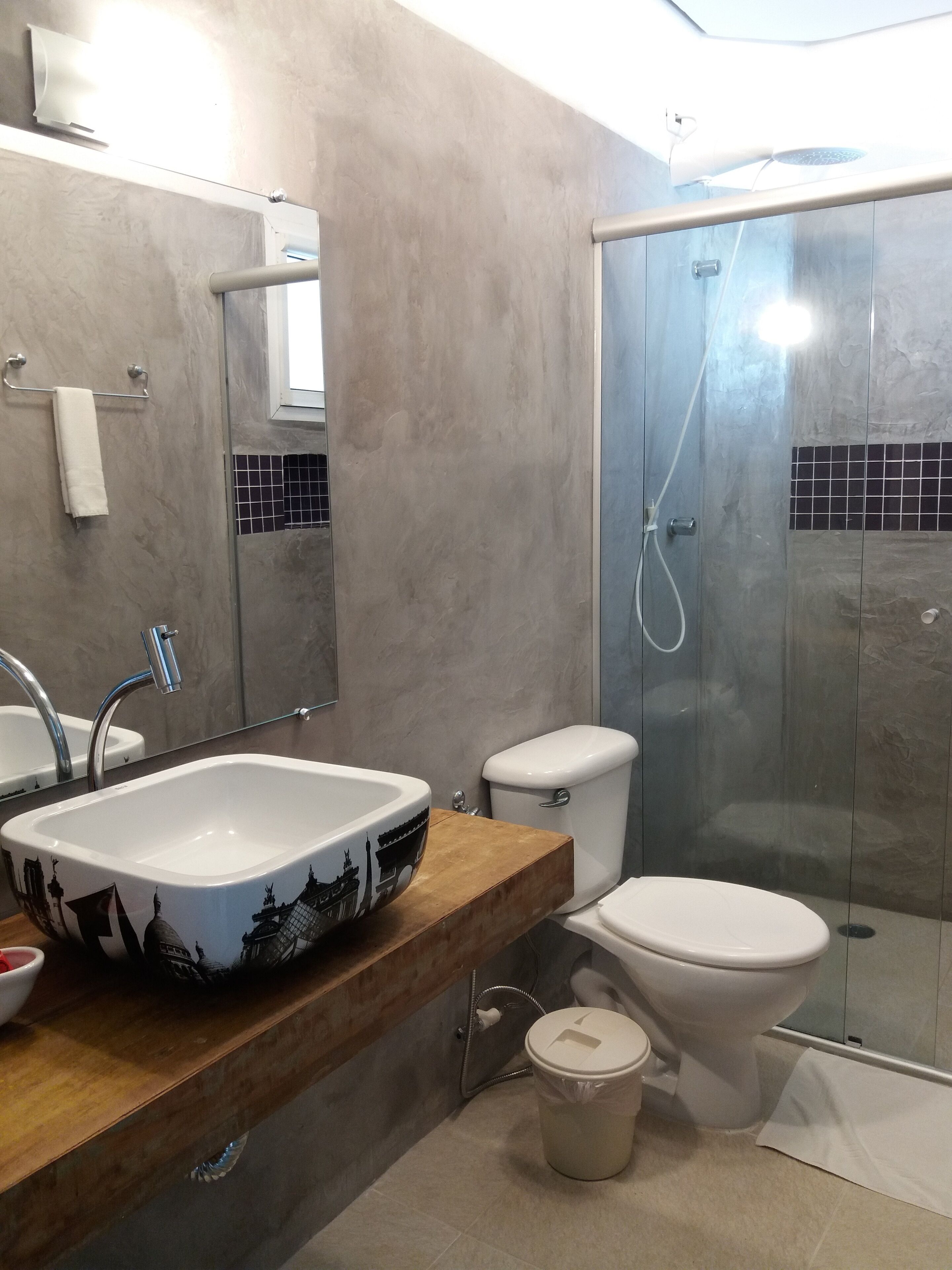 A modern bathroom with a large sink, toilet, and glass shower enclosure.