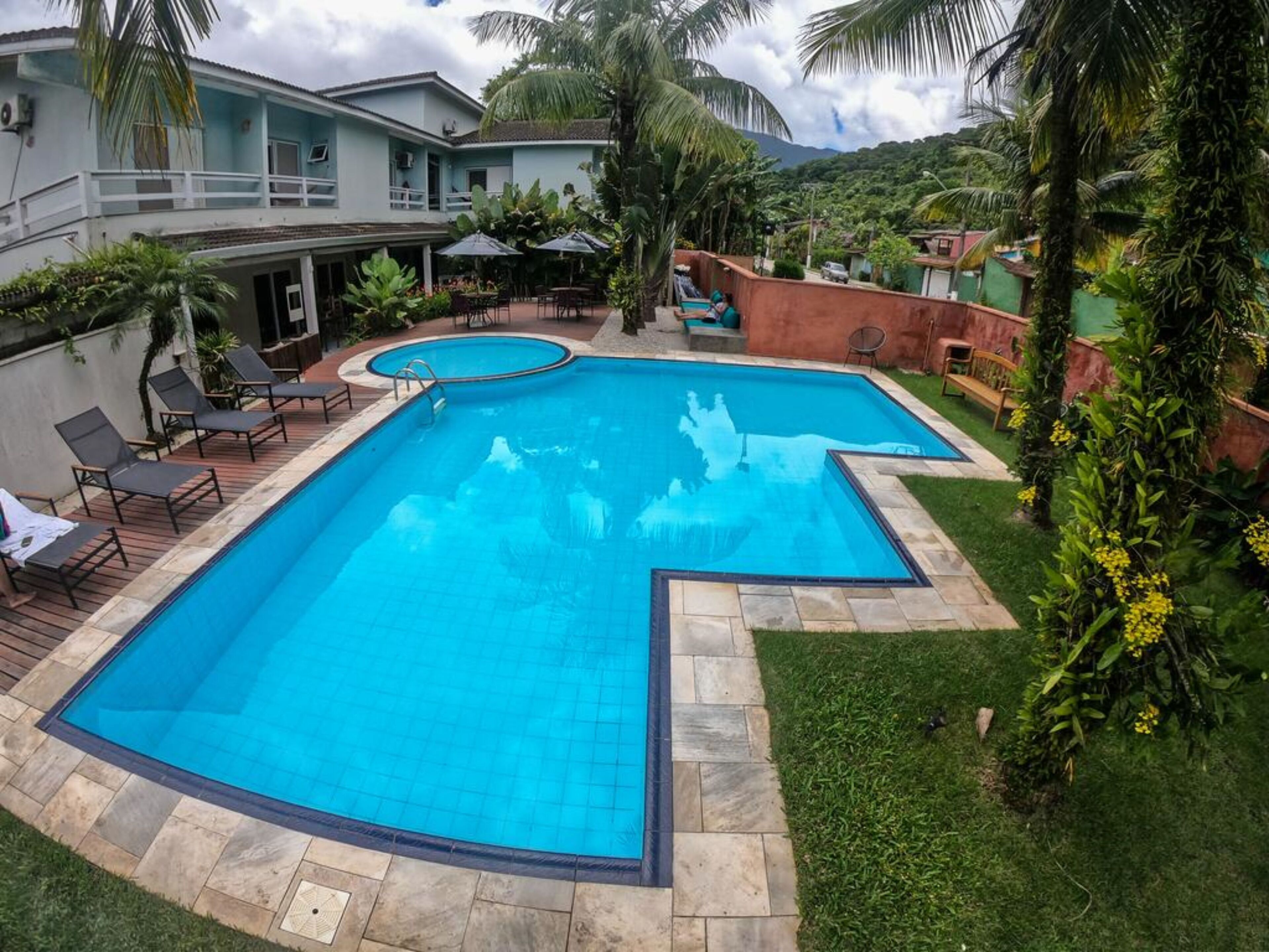 A rectangular swimming pool with a blue interior, surrounded by a stone deck and a grassy area.
