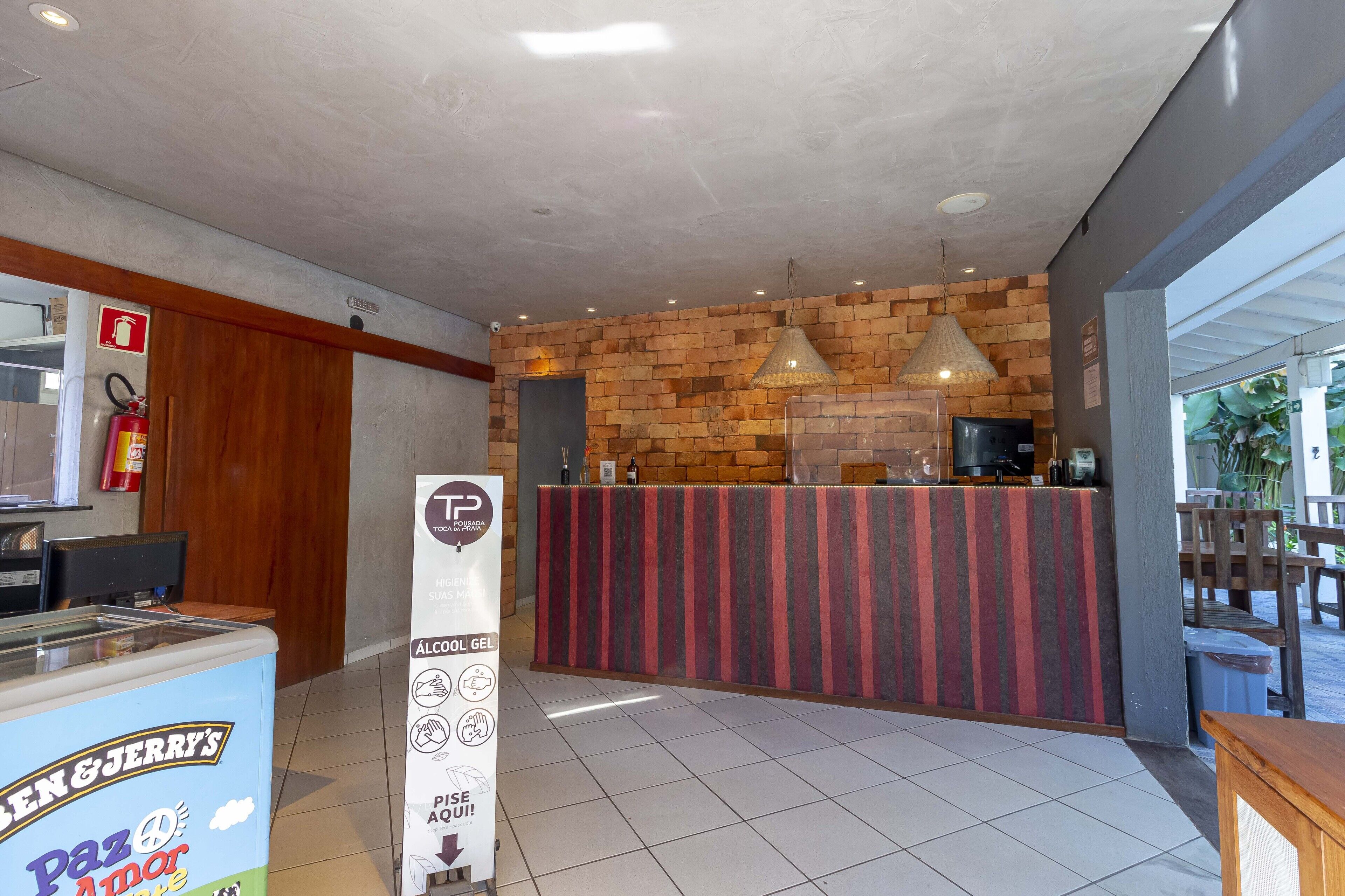 Zona de recepción con pared de ladrillo, mostrador y extintor.