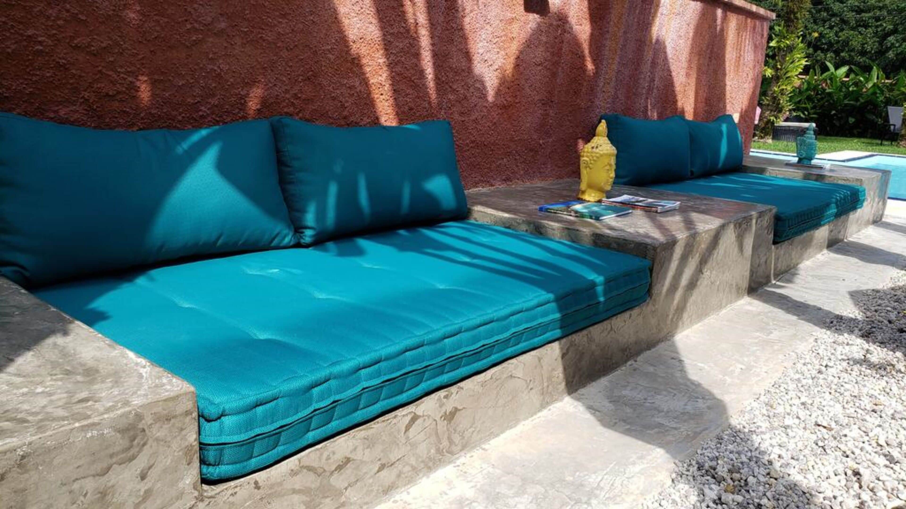 A section of a poolside area with a built-in bench and cushions.