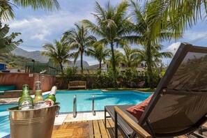 Una piscina al aire libre, sillones reclinables de piscina
