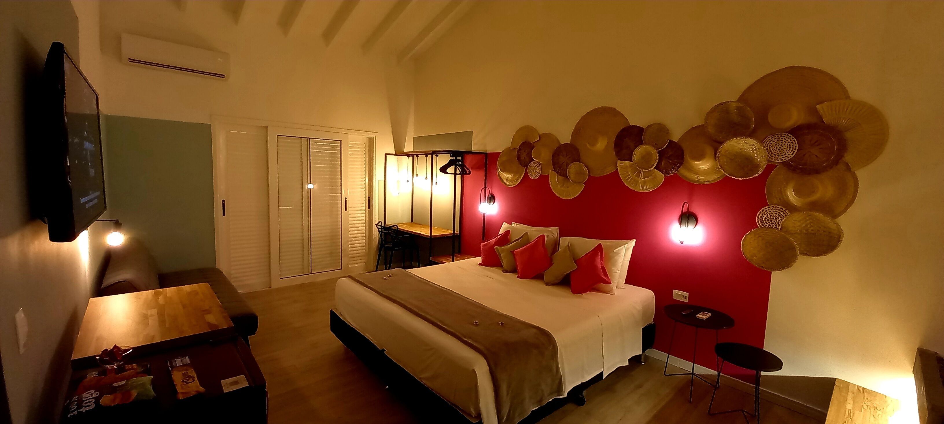 A bedroom with a bed, bedside tables, a TV, a wardrobe, and a wall with decorative plates.