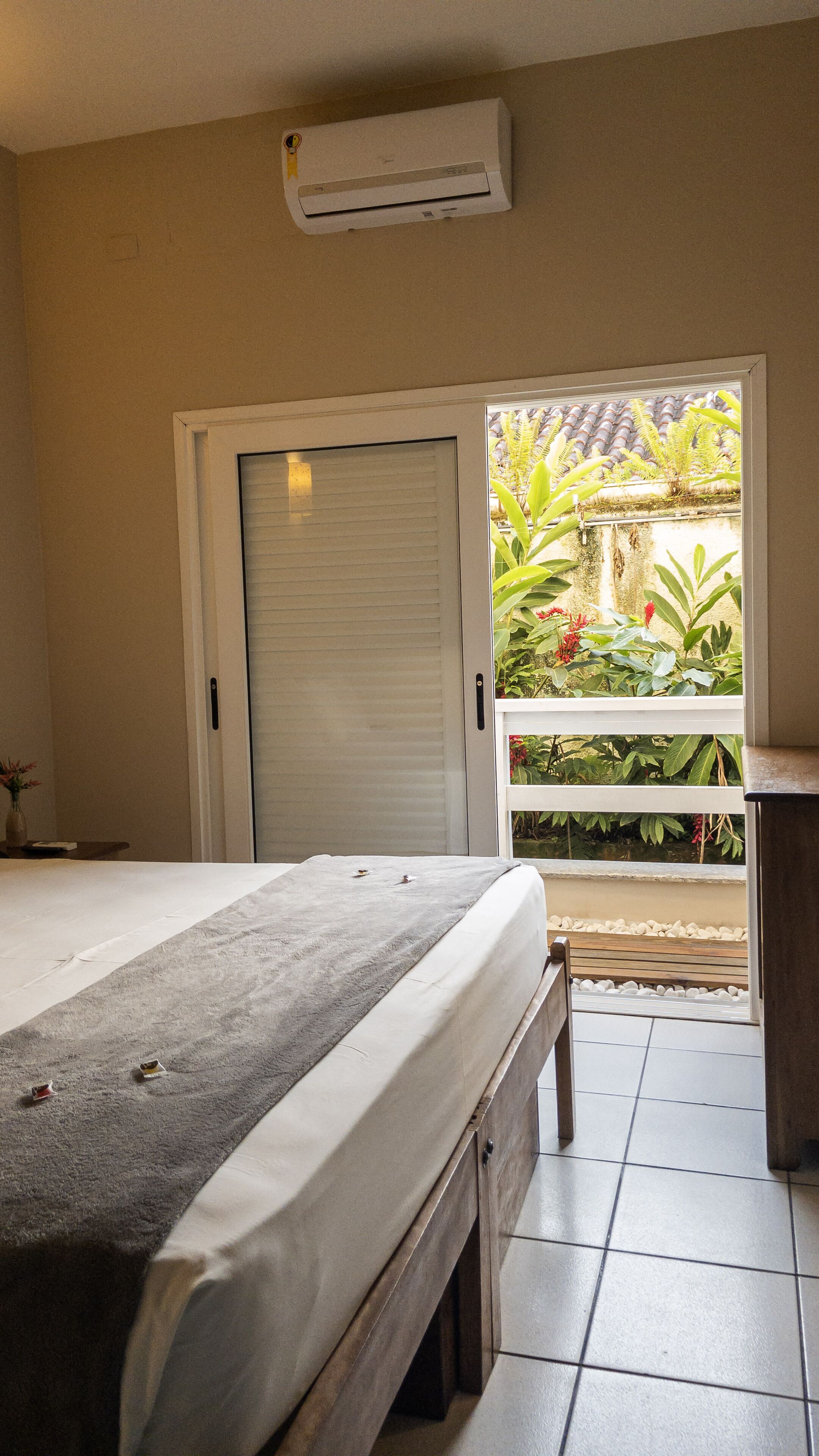 Un dormitorio con cama, una puerta corrediza a un balcón y un equipo de aire acondicionado en la pared.