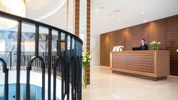 Un hall d’hôtel moderne avec un comptoir d’accueil, un escalier et un mur en bois.