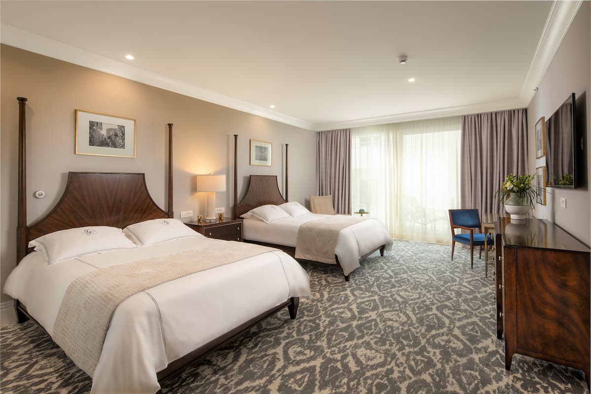 Una habitación de hotel con dos camas, un escritorio, una silla y un televisor.