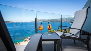 Un balcón con una mesa y dos sillas, con vistas a la costa.