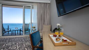 Une chambre d’hôtel avec balcon, une table à manger où le petit-déjeuner est servi, et un téléviseur fixé au mur.