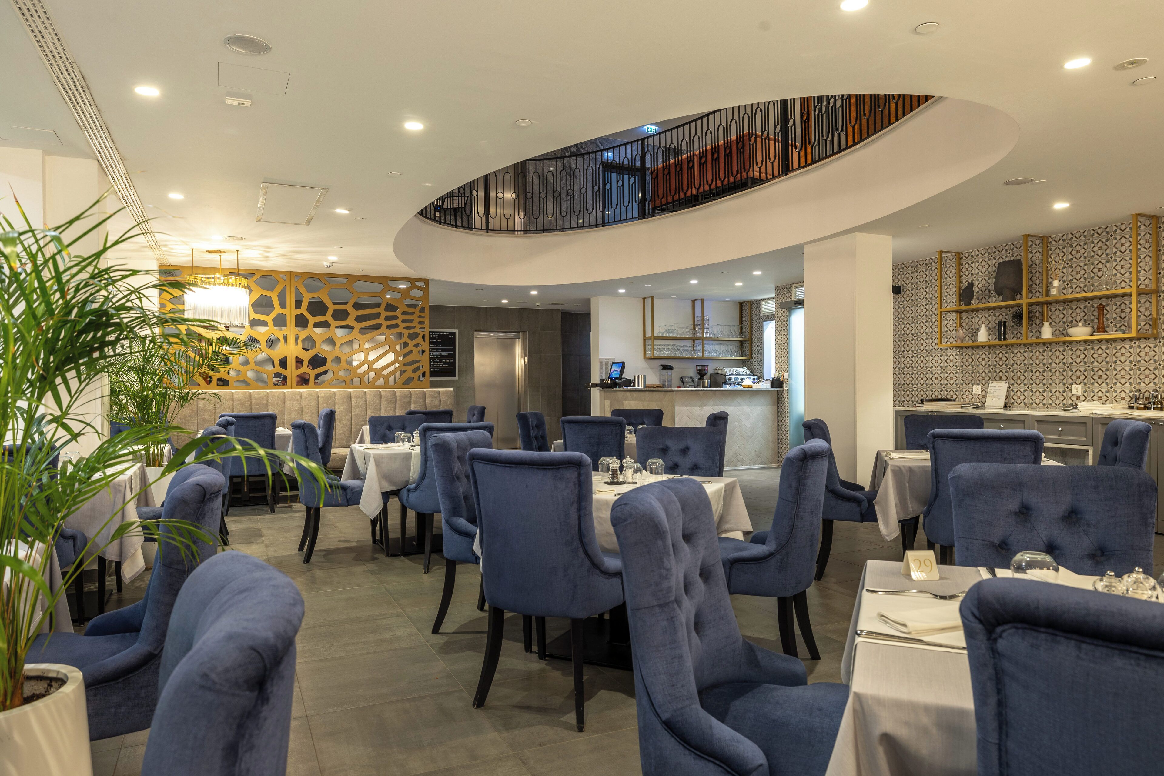 Un restaurant avec des chaises à revêtement bleu, des nappes blanches et un décor intérieur moderne.