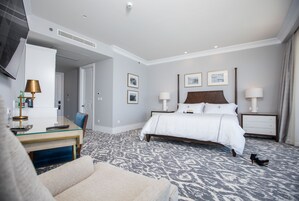 A hotel room with a bed, bedside tables, a desk, and a chair.