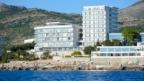 Un hotel frente al mar con varios balcones, una zona de piscina y vistas al océano.