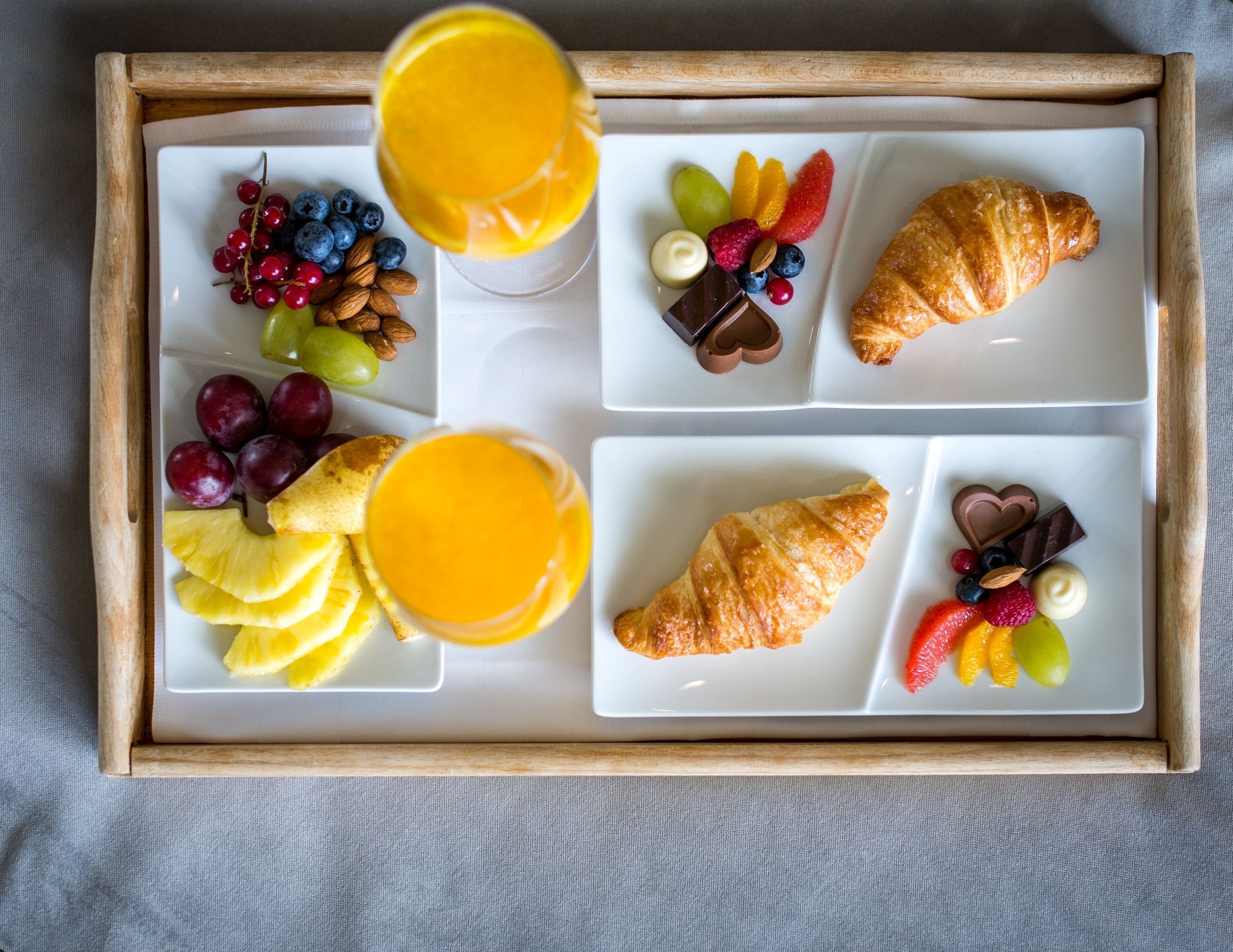 Ett frukostbricka med croissanter, frukt och choklad.