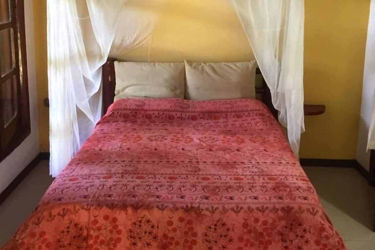 A bed with a canopy and a patterned bedspread.
