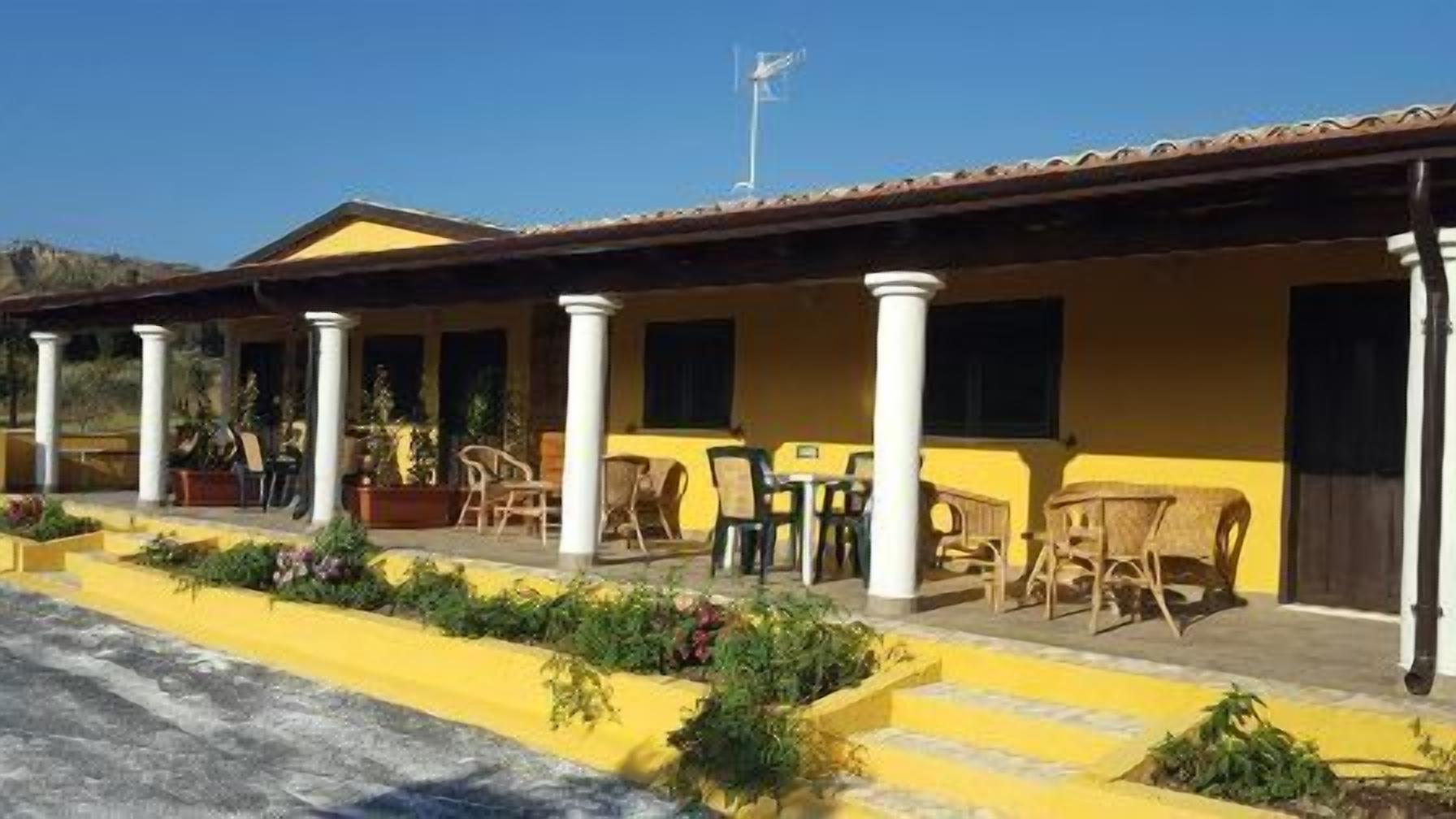 A building with a yellow facade, white columns, and outdoor seating.