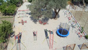 Une aire de jeux équipée de divers appareils, notamment des balançoires, un toboggan et un trampoline.