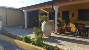Un bâtiment doté d’un patio couvert, de plantes en pot et de sièges extérieurs.