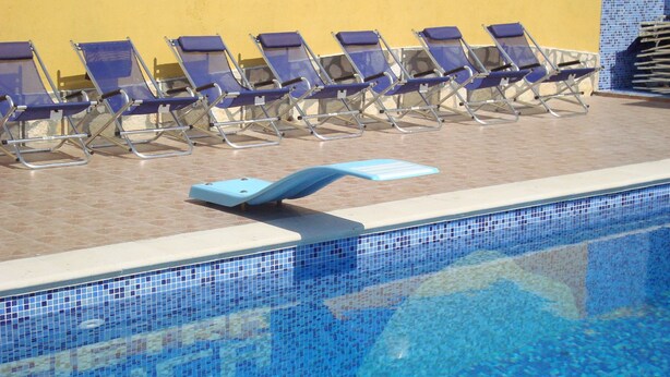 Un espace aménagé au bord de la piscine, avec des chaises longues et un plongeoir.
