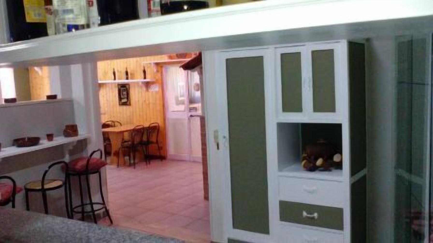 Una cocina compacta con comedor, armarios de madera y un taburete de bar.