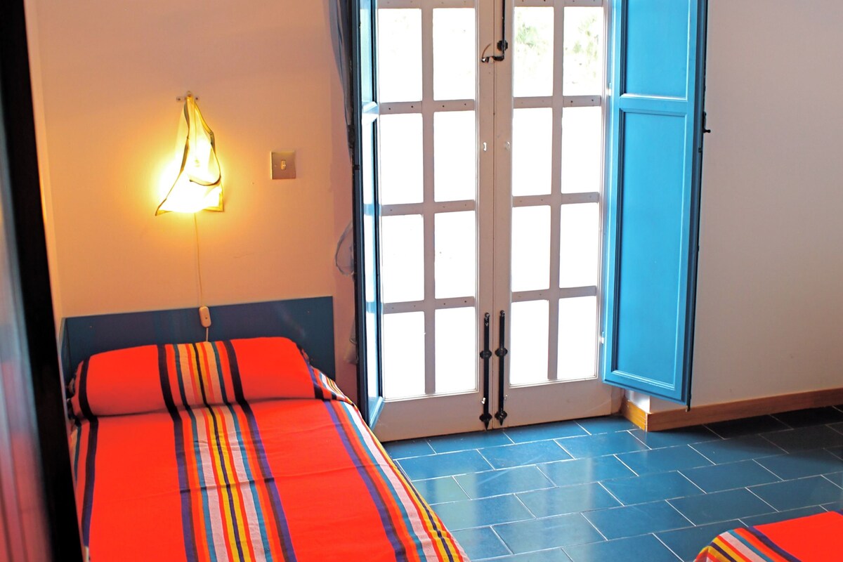 Une chambre avec deux lits, une fenêtre donnant sur un beau paysage et une porte.