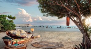Una spiaggia con una barca, un divano e una lampada sulla sabbia.
