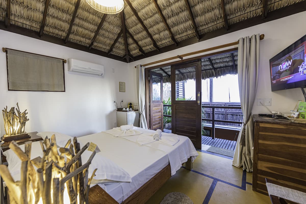 Ein Hotelzimmer mit Bett, Schreibtisch, Fernseher und einem Balkon mit Blick.
