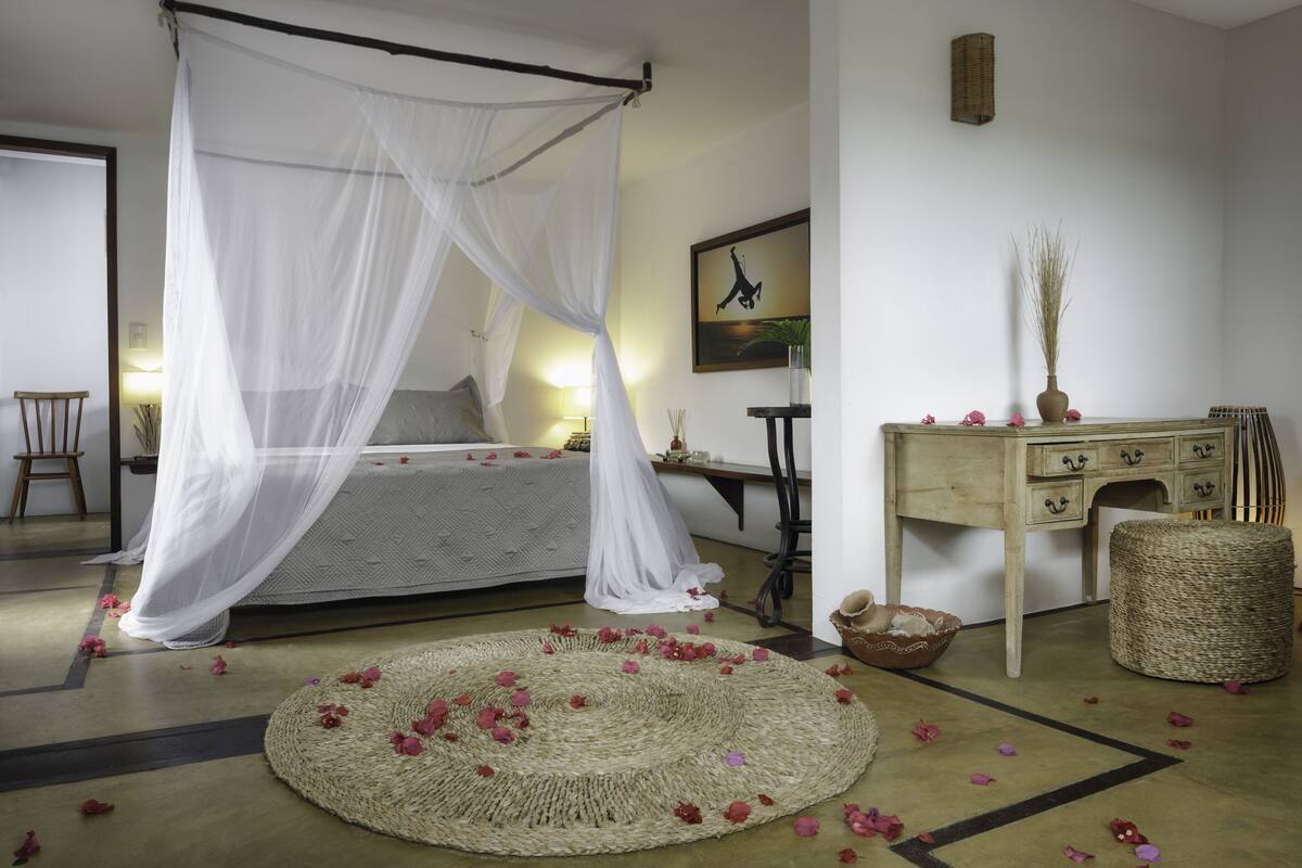 Ein Schlafzimmer mit einem Himmelbett, einem Schreibtisch mit Stuhl und einem Teppich.