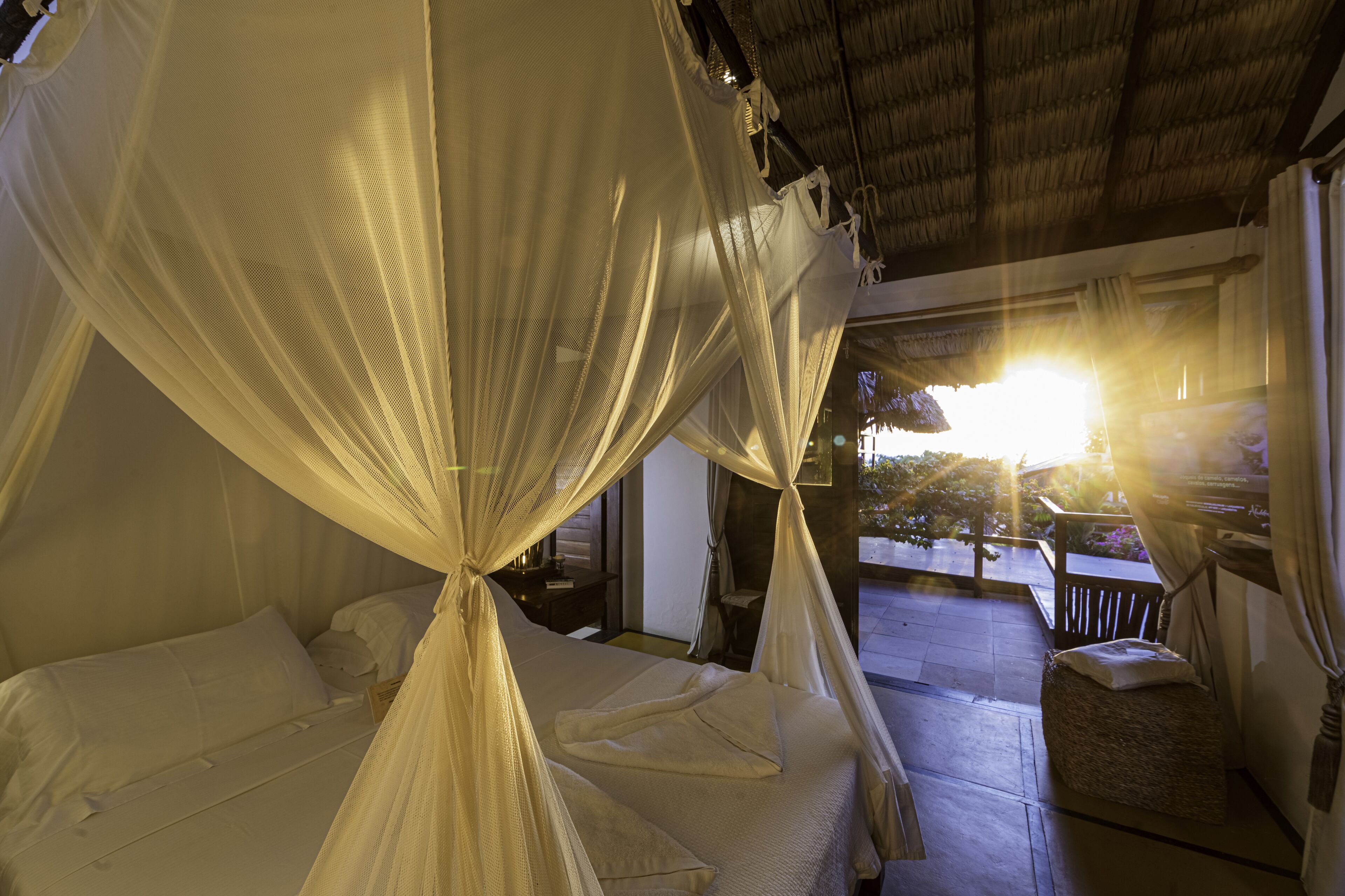 Una habitación con una cama bajo un dosel, un pequeño rincón de descanso y vistas al exterior.