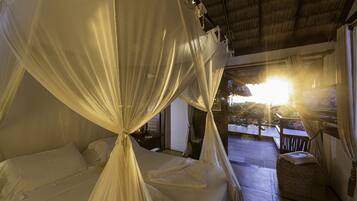 Una habitación con una cama bajo un dosel, un pequeño rincón de descanso y vistas al exterior.