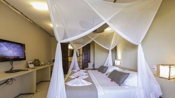 Una habitación de hotel con cama, televisión, escritorio y mesita de noche.