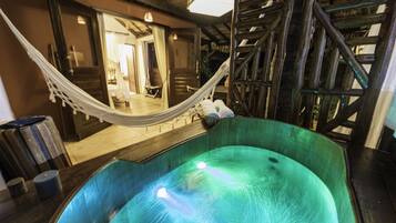 Un área de spa con un jacuzzi, una terraza de madera y una hamaca.