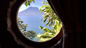 A window with a view of a lake and a mountain. - Hotel y Cafe La Casa del Mundo (Santa Cruz La Laguna)