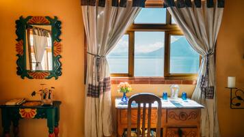 Una habitación con una mesa de madera, una silla, un espejo y una ventana con cortinas.