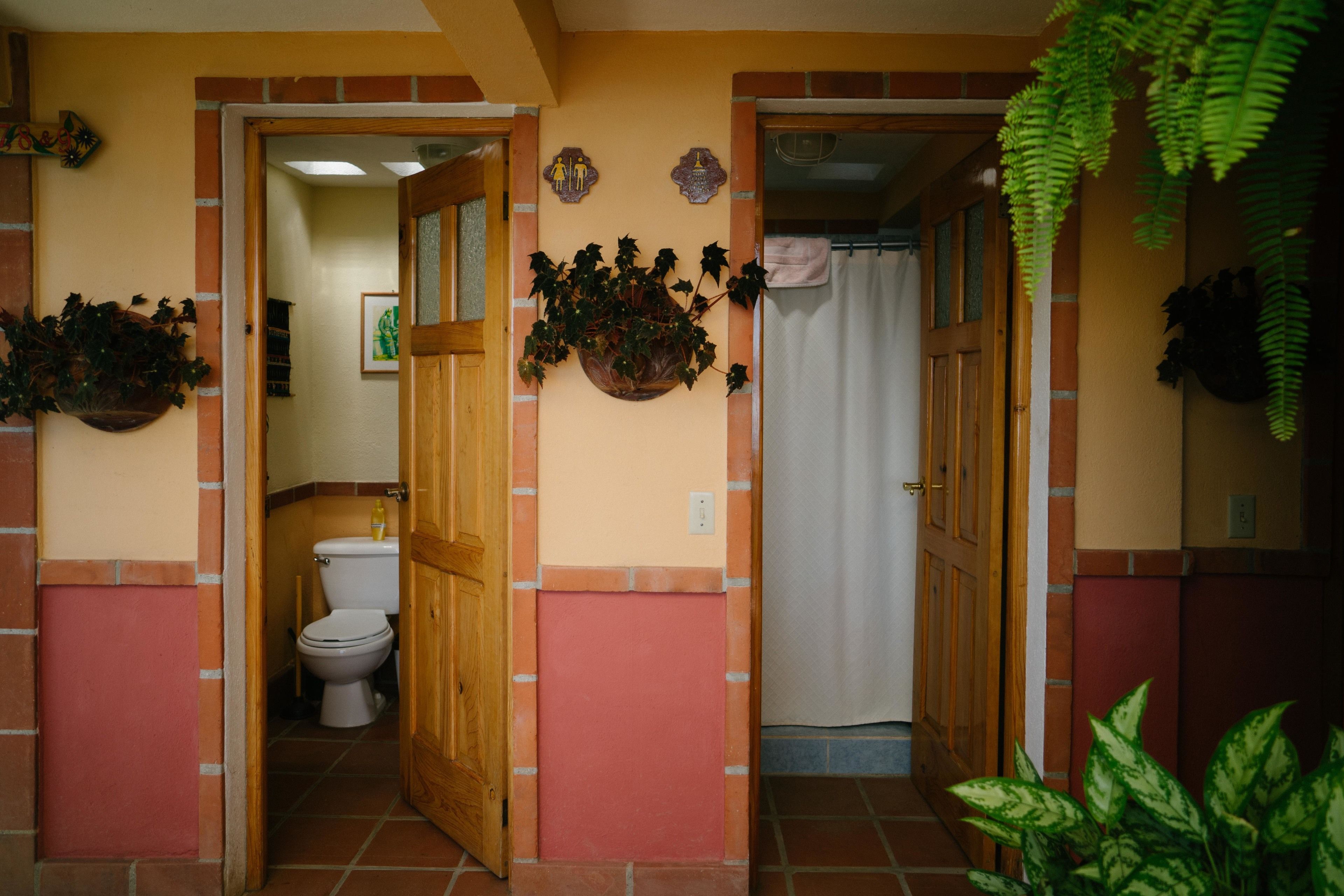 Un baño con inodoro, cortina de ducha y puerta de madera.