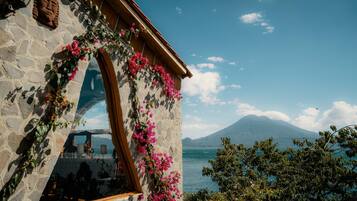 Un edificio de piedra con un arco de madera y flores rosadas.