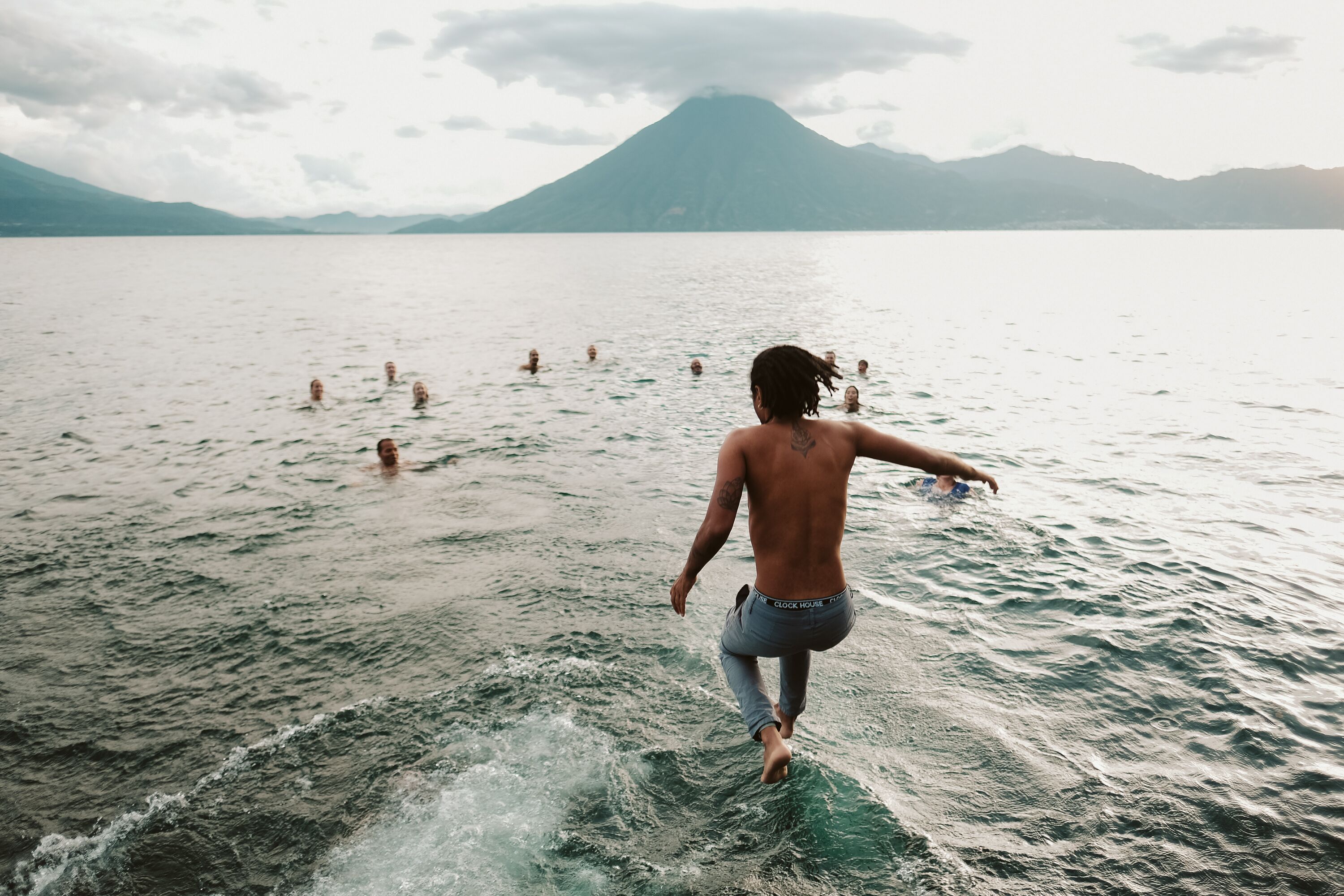 A person walking on a body of water with mountains in the background.