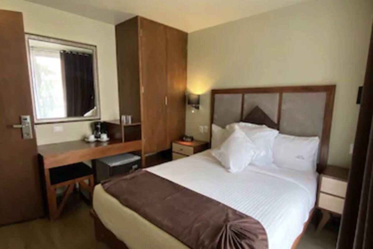 Une chambre d’hôtel comprenant un lit, un bureau, une armoire et une table de chevet.