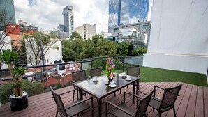 A rooftop terrace with a glass balustrade, a table with chairs, and a potted plant. - Suites Lerma (Mexico City)