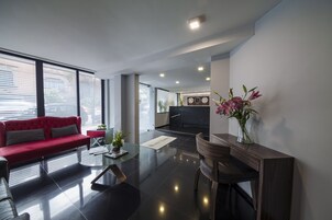 A modern living room with a red sofa, a coffee table, and a wooden side table with a vase of flowers.