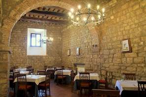 A restaurant with stone walls, wooden tables, and chairs. - Relais il Castello (Monte Castello di Vibio)