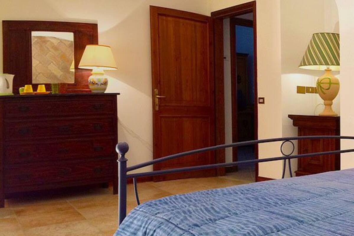 A bedroom with a bed, a dresser, a television, and a door.