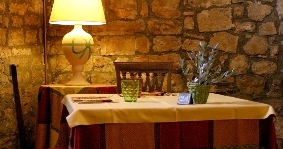 Een tafel met een wit tafelkleed, een groene vaas en een lamp met een groen ontwerp.