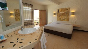 A hotel room with a large mirror, a sink, a bed, and a painting on the wall. - Hotel Plaza Tangolunda (Santa María Huatulco)