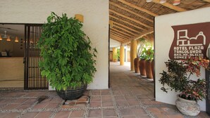 A hotel entrance with a large potted plant, a signboard, and a tiled floor. - Hotel Plaza Tangolunda (Santa María Huatulco)