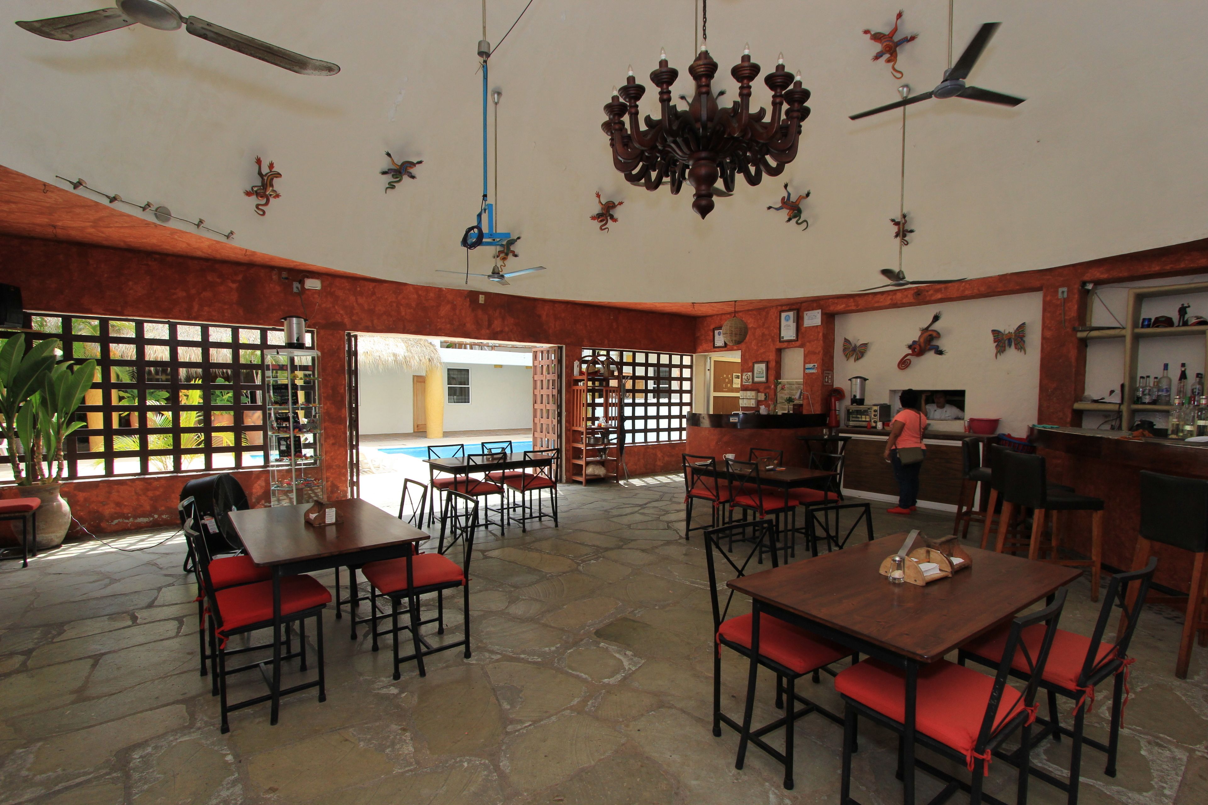 Un restaurante con suelo de piedra, sillas rojas acolchadas y una zona de bar.
