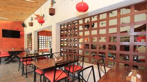 A restaurant with wooden tables and red cushioned chairs, a wooden ceiling, and a red decorative element. - Hotel Plaza Tangolunda (Santa María Huatulco)