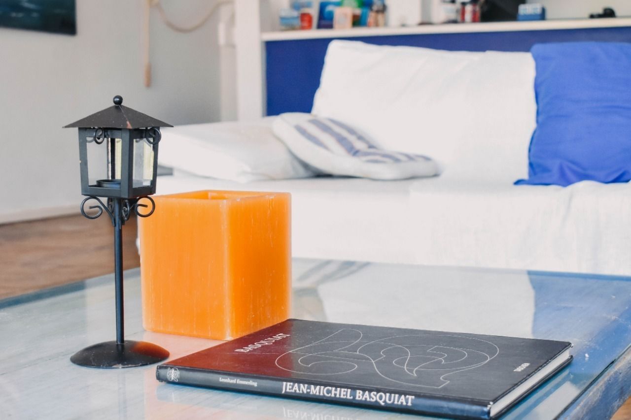 A room with a glass table displaying a book titled 'JEAN-MICHEL BASQUIAT' and a candle.